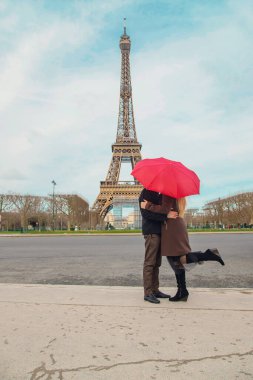 Paris 'teki Eyfel Kulesi yakınlarında kırmızı şemsiyeli aşıklar. Seçici odaklanma. Doğa.