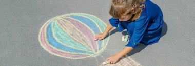 Çocuk kaldırıma tebeşirle çiziyor. Seçici odak.