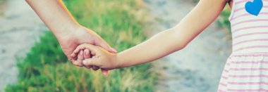 Anne ve çocuk el ele gider. Seçici odaklanma. Doğa.