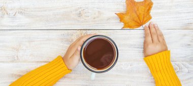 Elinde bir fincan çay olan bir çocuk. Seçici odak. Sonbahar.