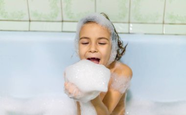 Çocuk sabunlu bir küvette banyo yapıyor. Seçici odak.
