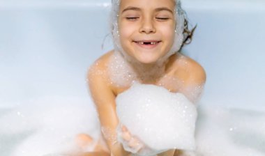 Çocuk sabunlu bir küvette banyo yapıyor. Seçici odak.