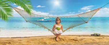 Çocuk sahilde hindistan cevizi içer. Seçici odak.