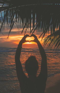 Kız gün batımında kalp elleri yapıyor. Sri Lanka. Seçici odaklanma. Doğa.