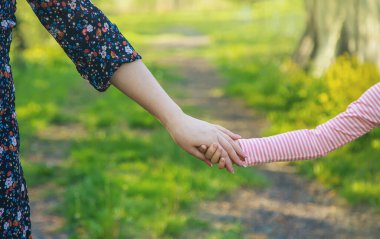 Annesiyle birlikte bir çocuk ellerinden tutar. Seçici odaklanma. Doğa.