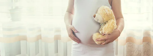 おもちゃを持った妊婦がお腹を抱えている 選択的フォーカス — ストック写真