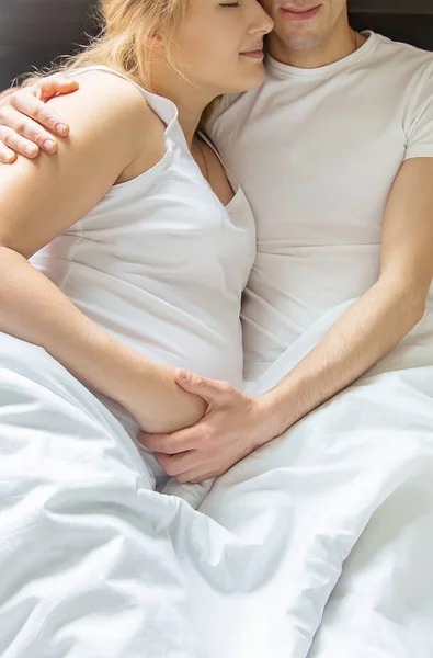 在床上抱着男人的孕妇 有选择的重点 — 图库照片