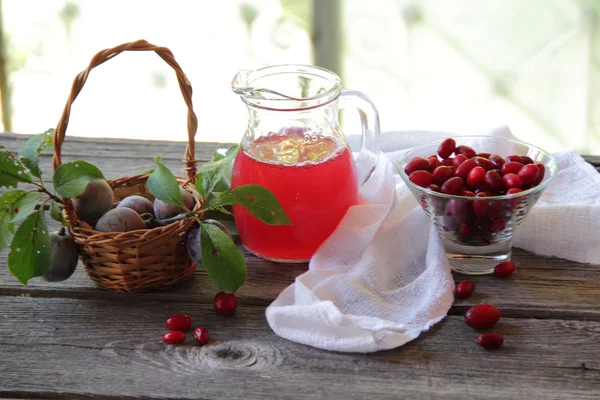 Compote of dogwood and fresh plums in a basket — Stock Photo, Image