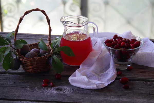 Kompot z svída a čerstvé švestky v košíku — Stock fotografie