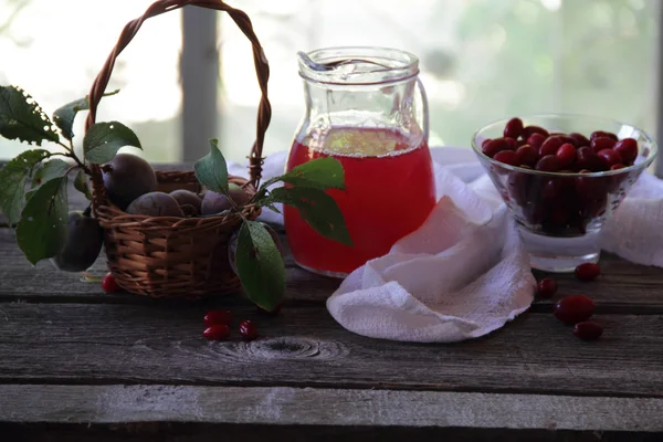 Compote of dogwood and fresh plums in a basket — Stock Photo, Image