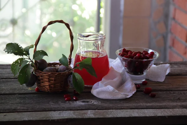 Kompot z svída a čerstvé švestky v košíku — Stock fotografie