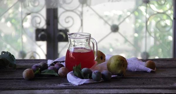 Compota de ciruelas y peras en una jarra transparente —  Fotos de Stock