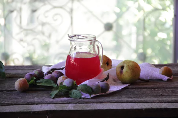 Compote of plums and pears in a transparent jug — Stock Photo, Image