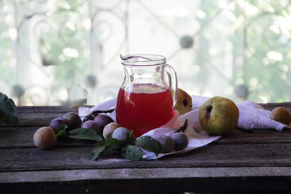 Compote of plums and pears in a transparent jug — Stock Photo, Image