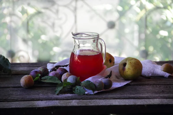 Compote of plums and pears in a transparent jug — Stock Photo, Image