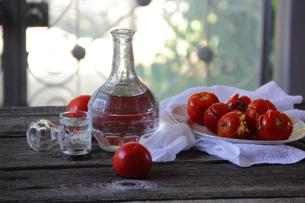 Vodka in a decanter and stuffed marinaded tomatoes — Stock Photo, Image