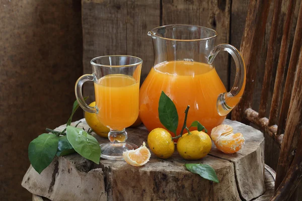 Jugo de mandarina en una jarra y mandarinas frescas —  Fotos de Stock