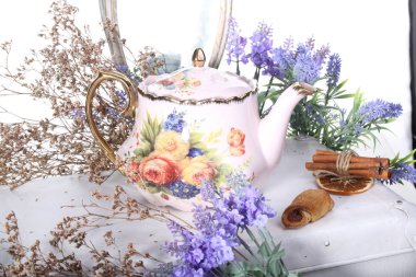 Porselen çaydanlık beyaz bir tabloda çay ve eflatun çiçekli