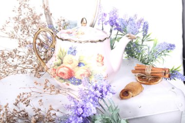 Porselen çaydanlık beyaz bir tabloda çay ve eflatun çiçekli