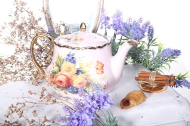 Porselen çaydanlık beyaz bir tabloda çay ve eflatun çiçekli