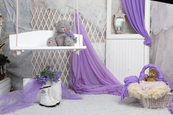 Ein Spielzeugbär sitzt auf einer Schaukel in einem hellen Raum — Stockfoto