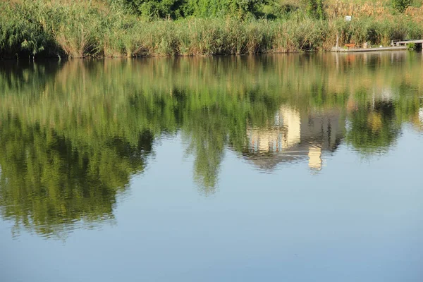 Gebouw en bomen weerspiegeld in de rivier — Stockfoto