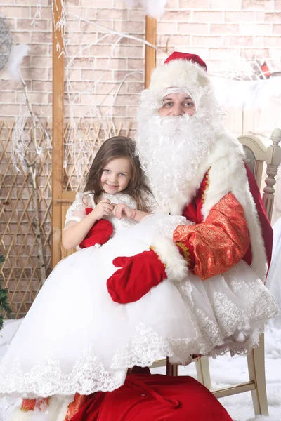 Babbo Natale con un berretto rosso che tiene un bambino in ginocchio — Foto Stock