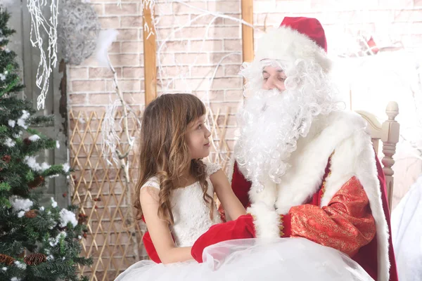 Santa Claus v červené víčko drží dítě na kolenou — Stock fotografie