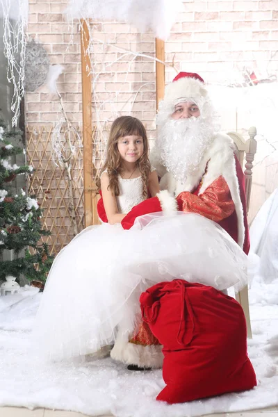 Santa Claus v červené víčko drží dítě na kolenou — Stock fotografie