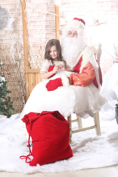 Noel Baba'ya dizlerinin üzerinde bir bebek tutan kırmızı bere — Stok fotoğraf