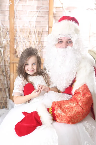 Noel Baba'ya dizlerinin üzerinde bir bebek tutan kırmızı bere — Stok fotoğraf