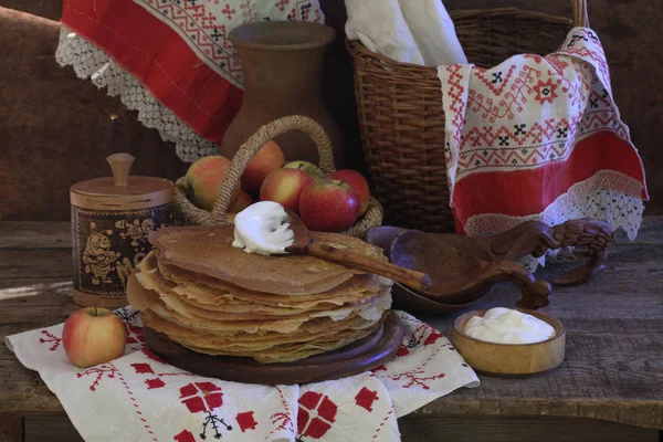 Stillleben mit Pfannkuchen, saurer Sahne und Äpfeln auf einem Holztisch — Stockfoto