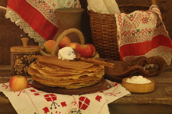 Pannkakor med gräddfil och äpplen på ett träbord — Stockfoto