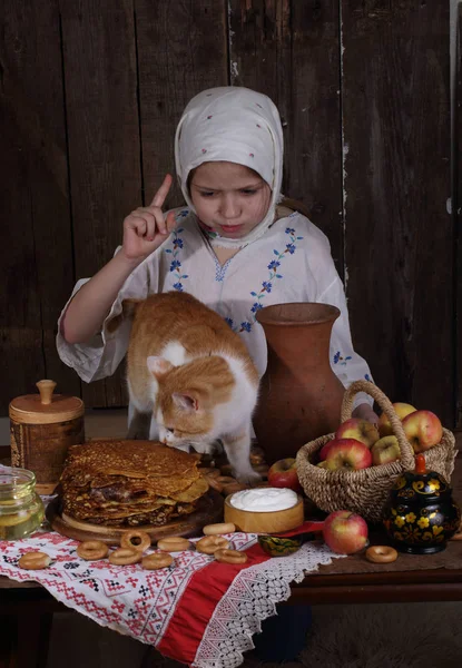 Το κορίτσι στο τραπέζι των διακοπών με τη γάτα. Καρναβάλι — Φωτογραφία Αρχείου