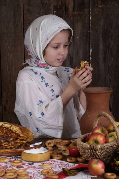 Mädchen isst Pfannkuchen während maslenitsa — Stockfoto