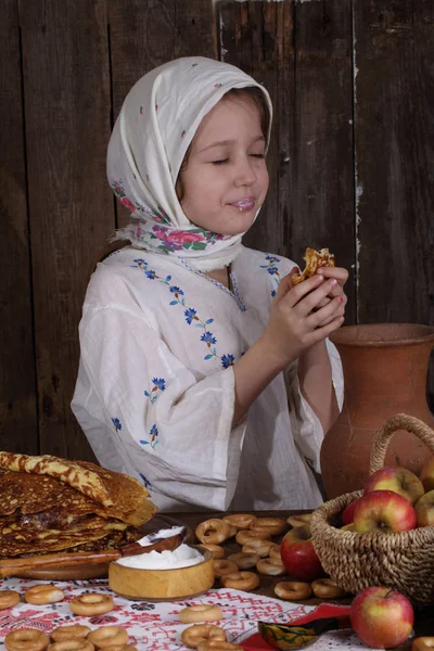 Mädchen isst Pfannkuchen während maslenitsa — Stockfoto