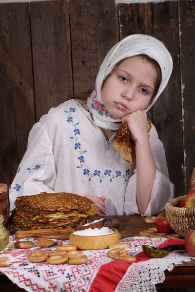 Ragazza mangiare frittelle durante Maslenitsa — Foto Stock