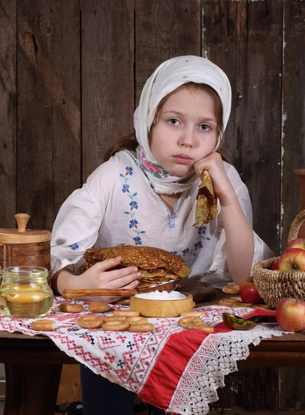 Flicka äter pannkakor med gräddfil under karnevalen — Stockfoto