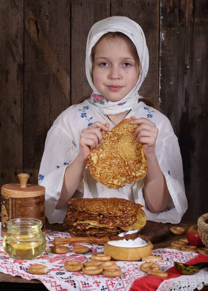 Dívka jíst palačinky během Maslenica — Stock fotografie