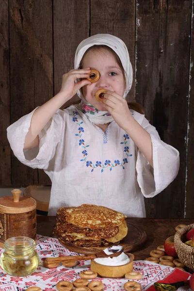 A lány az ünnepi asztalra, bagel és a palacsinta — Stock Fotó