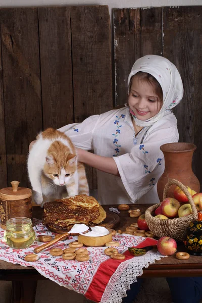 La ragazza al tavolo delle vacanze con il gatto. Carnevale — Foto Stock