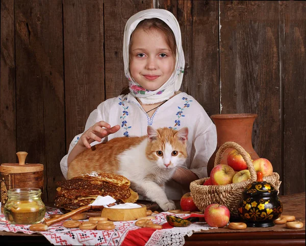 La chica en la mesa de vacaciones con el gato. Carnaval. —  Fotos de Stock