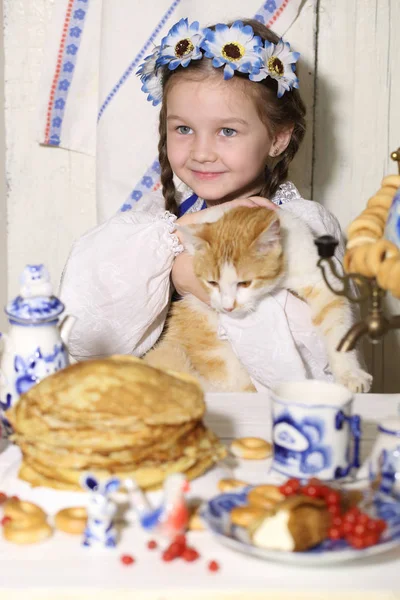 Дівчина і імбирний кіт за столом — стокове фото