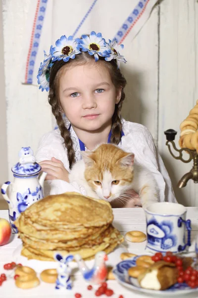 Дівчина і імбирний кіт за столом — стокове фото