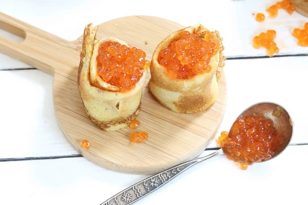 Pancakes with red caviar on the wooden table. — Stock Photo, Image