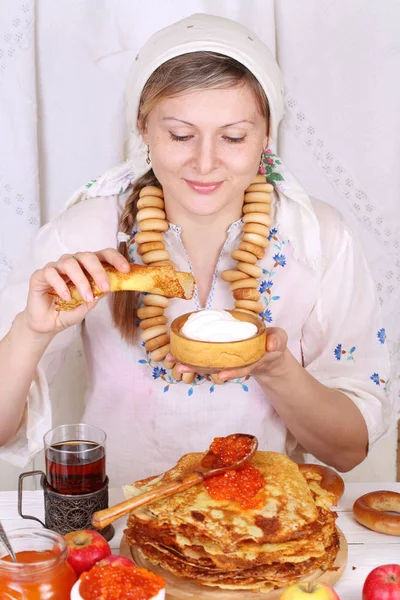 La ragazza al tavolo festivo che mangia frittelle — Foto Stock