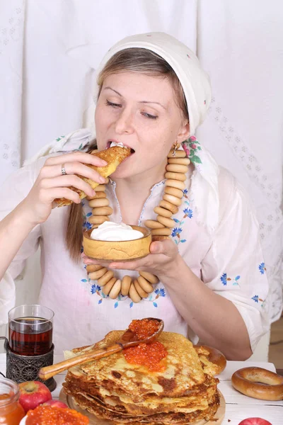Ragazza in una sciarpa mangiare frittelle con panna acida — Foto Stock