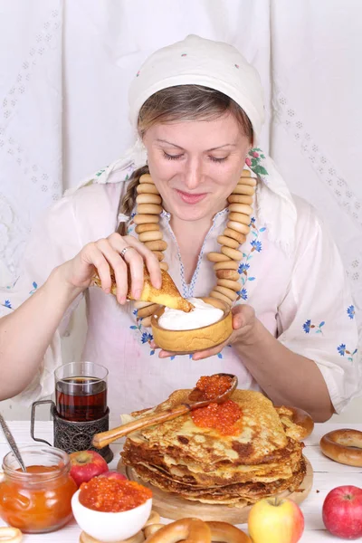 Meisje in een sjaal eten van pannenkoeken met zure room — Stockfoto