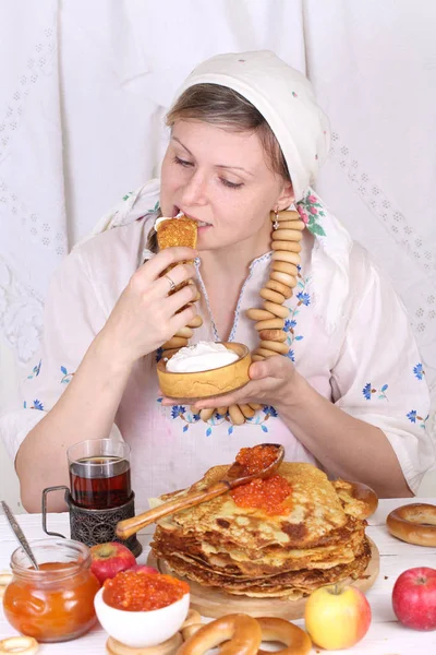 Het meisje aan de feestelijke tafel pannenkoeken eten — Stockfoto