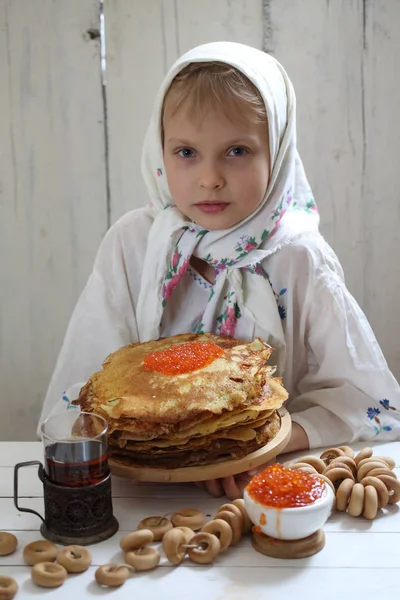 Flickan sitter på semestern bordet. Pannkakor med röd kaviar — Stockfoto